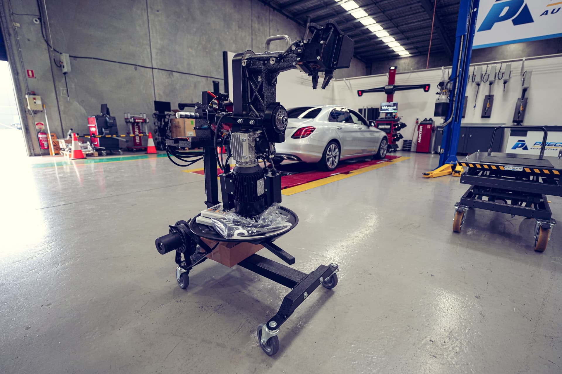Diagnostic equipment on a clean workshop floor with a car on a hoist