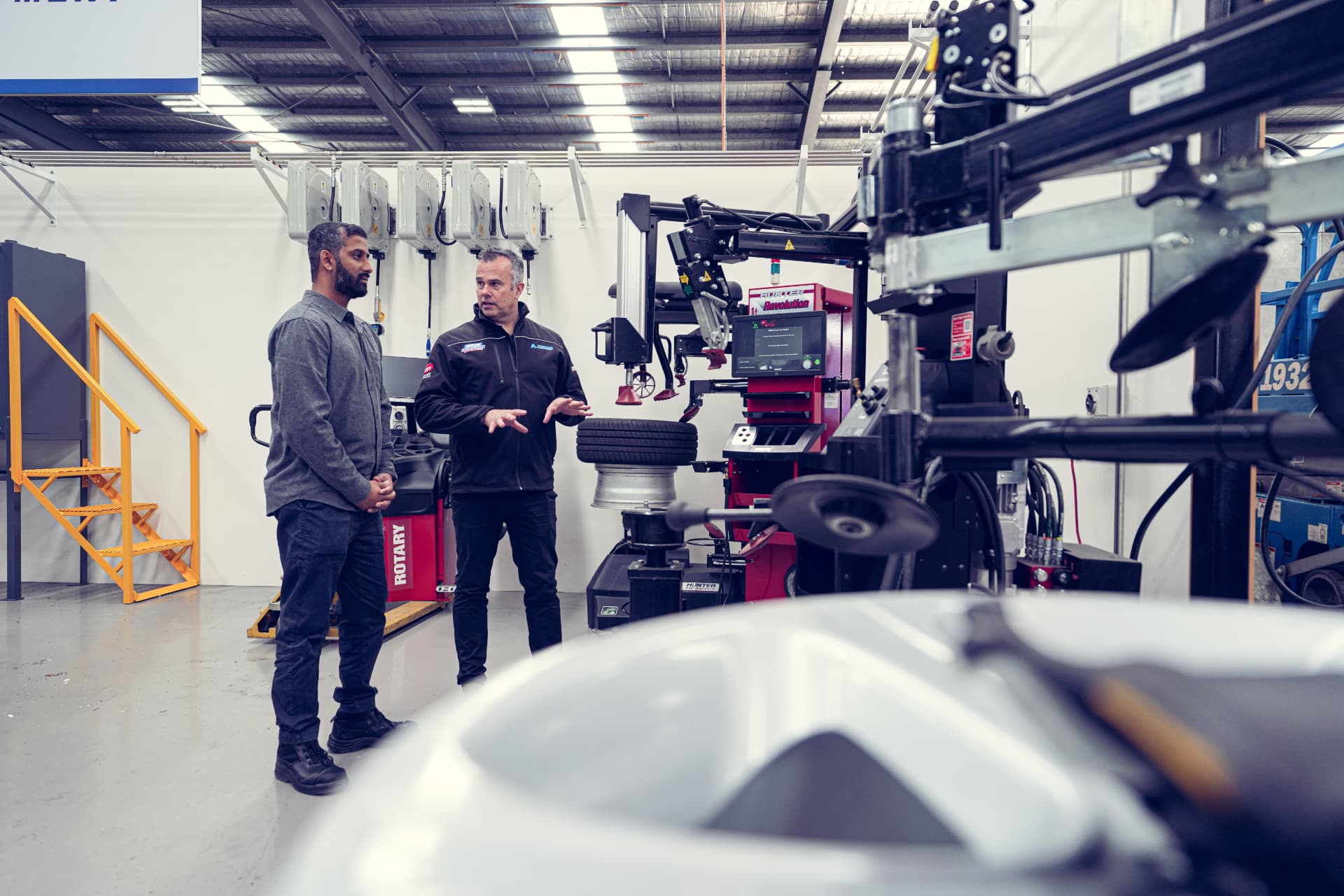 Precision team members discussing tyre service equipment with a workshop owner